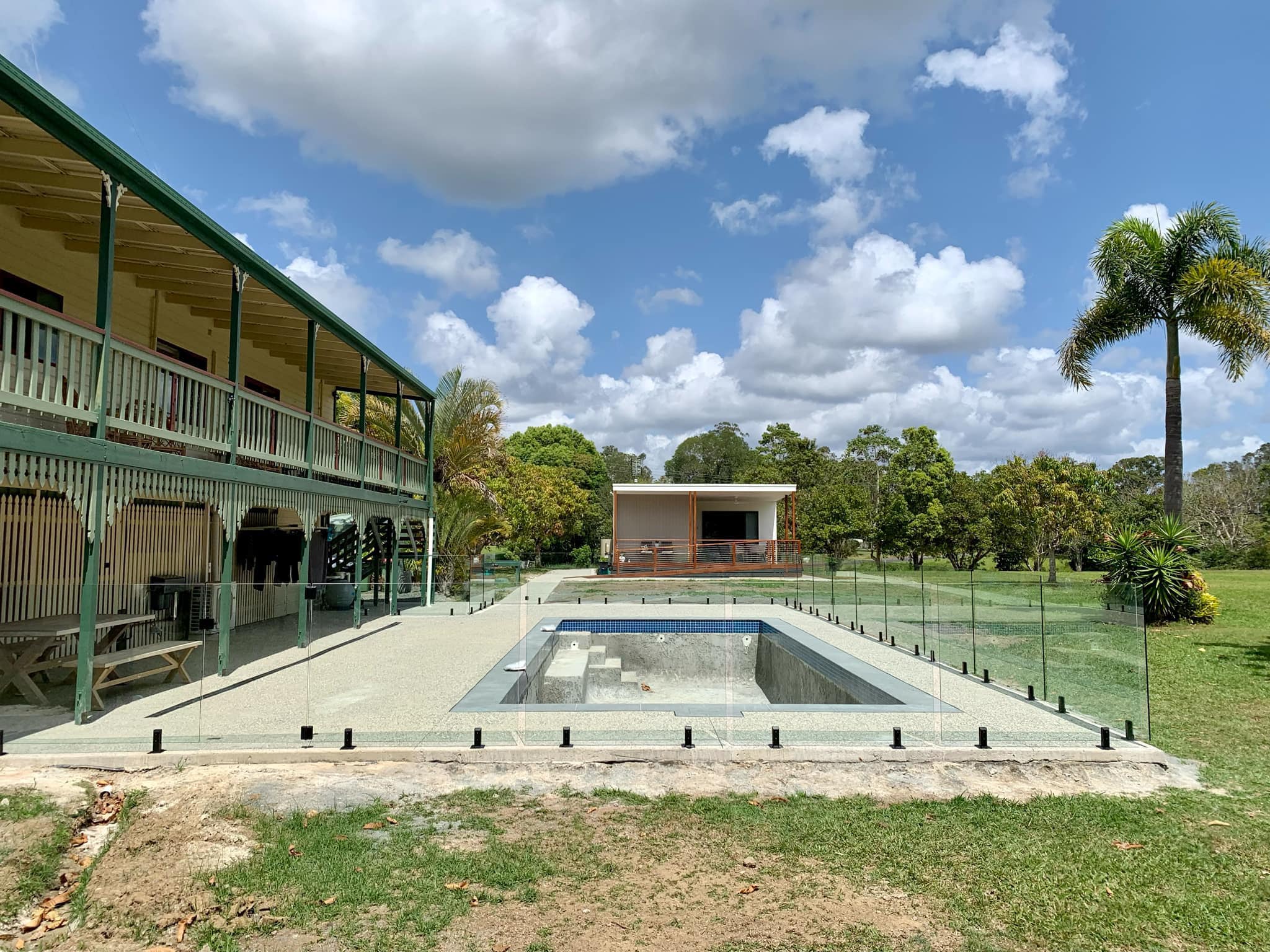 Frameless glass pool fence with black spigots at an acreage Queenslander home
